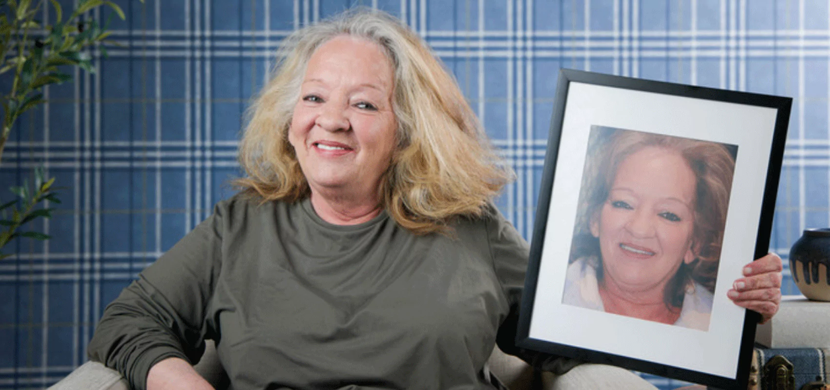 Smiling woman holding a framed photo of herself before dental treatment, showing a clear before-and-after transformation.