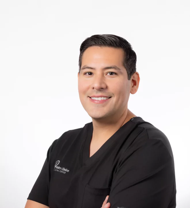 Dr. Gemmell, smiling dental professional in black scrubs with arms crossed.
