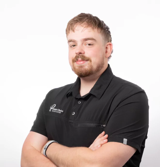 Jacob from Premier Choice Dental Center wearing a black polo shirt and smiling with arms crossed.