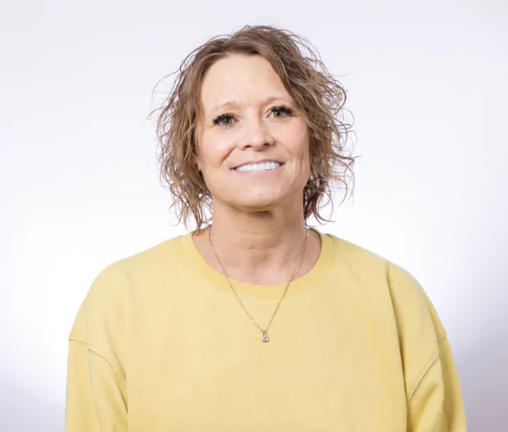 Woman in yellow shirt smiling with zirconia fixed bridge.