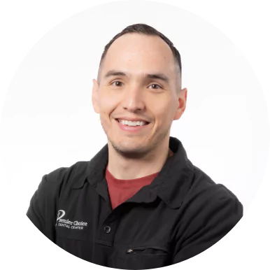 Smiling male dental team member in black Premier Choice Dental Center uniform with folded arms.